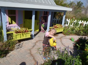 Girls watering plants outside playhouse
